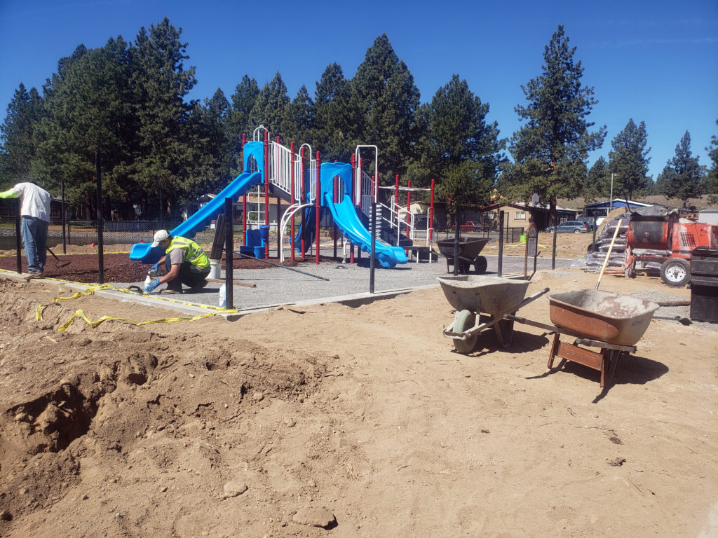 A playground with a slide in the dirt.