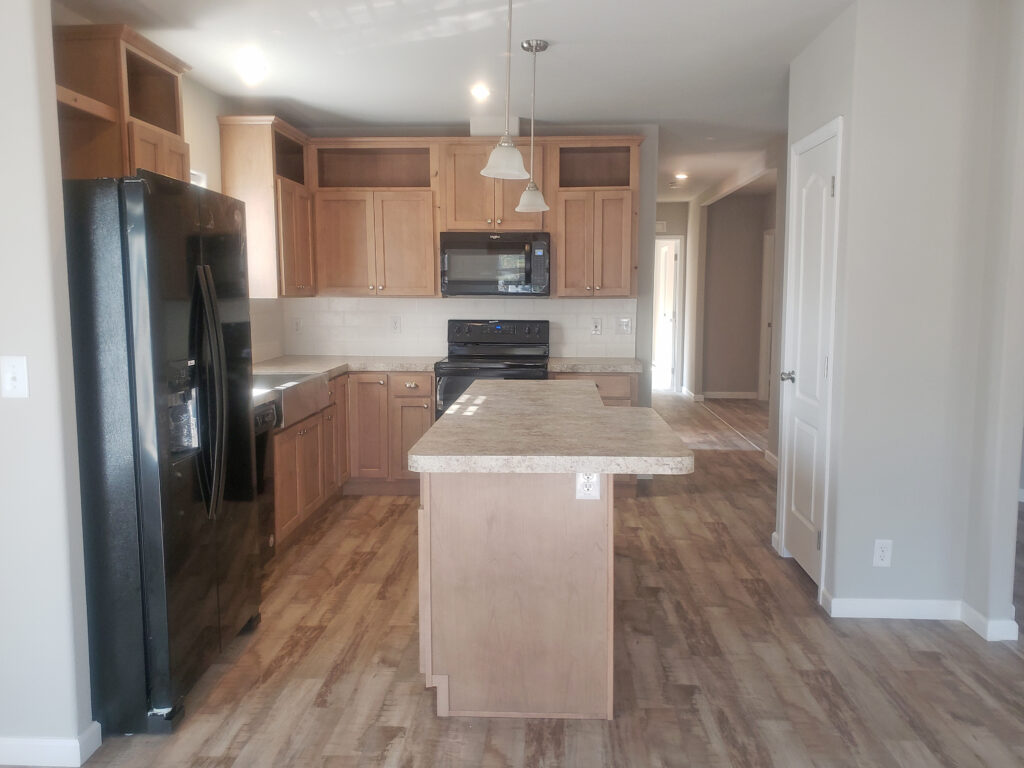 An empty kitchen with wood cabinets and hardwood floors.