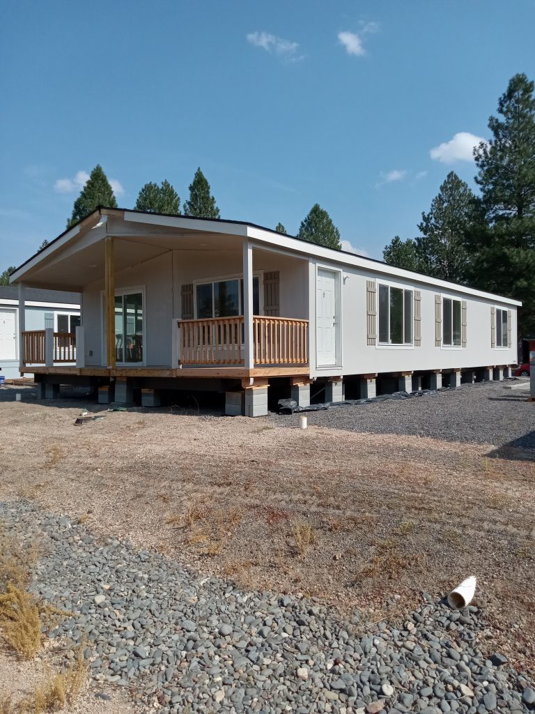 A mobile home is sitting on a gravel lot.