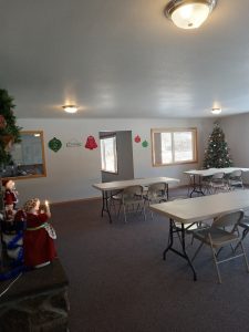 A room with tables and chairs decorated with a festive Christmas tree.