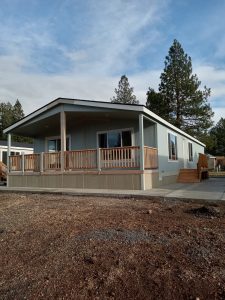 A manufactured home with a porch and a driveway.