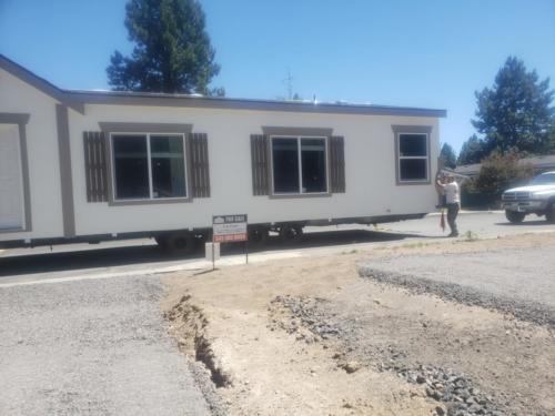 A white mobile home with a trailer in front of it.