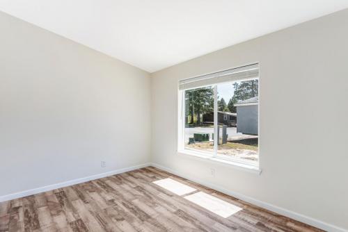 An empty room with hardwood floors and a window.