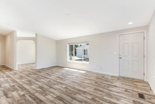 An empty living room with wood floors and white walls.