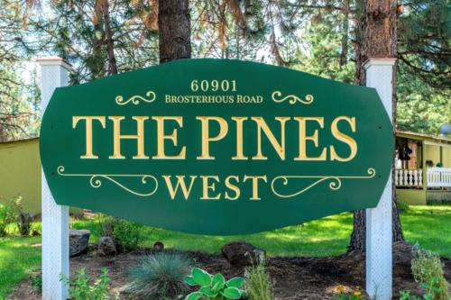The pines west sign in front of trees.