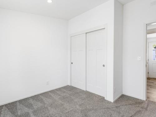 An empty room with white walls and gray carpet.