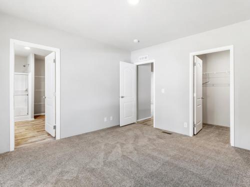 An empty room with gray carpet and closets.