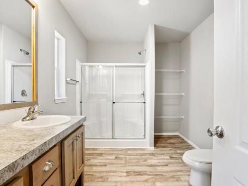 A bathroom with wood floors and a walk in shower.