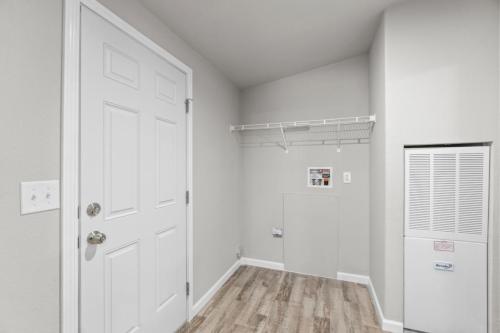 A hallway with a white door and wood floor.