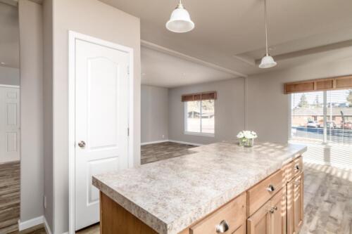 An empty kitchen with hardwood floors and a granite counter top.