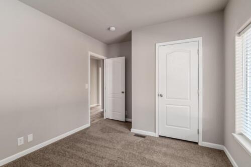 An empty room with gray carpet and white doors.