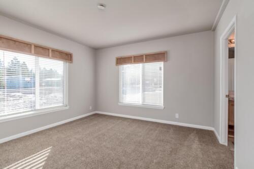 An empty room with beige carpet and a window.