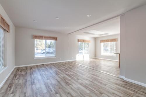 Empty living room with hardwood floors and windows.
