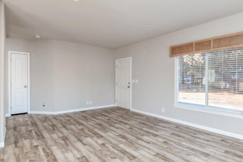Empty living room with hardwood floors and white walls.