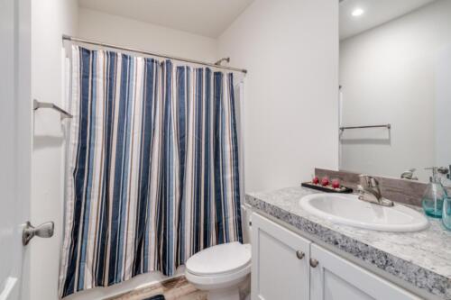 A bathroom with a blue striped shower curtain.