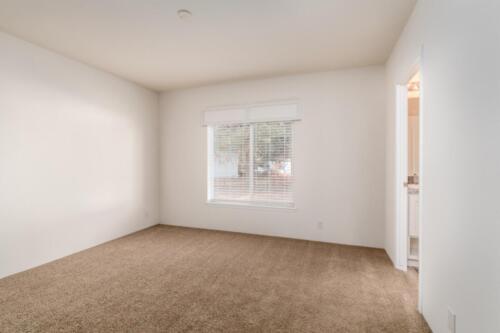 An empty room with tan carpet and white walls.
