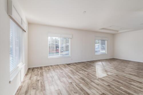 Empty living room with hardwood floors and windows.