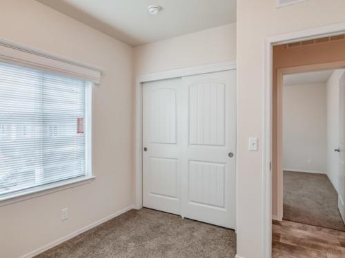 An empty room with two closets and a door.