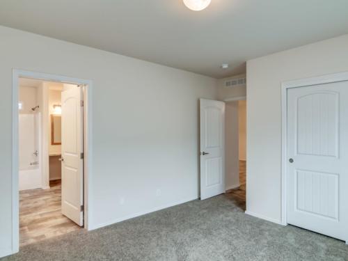 An empty room with two doors and carpet.